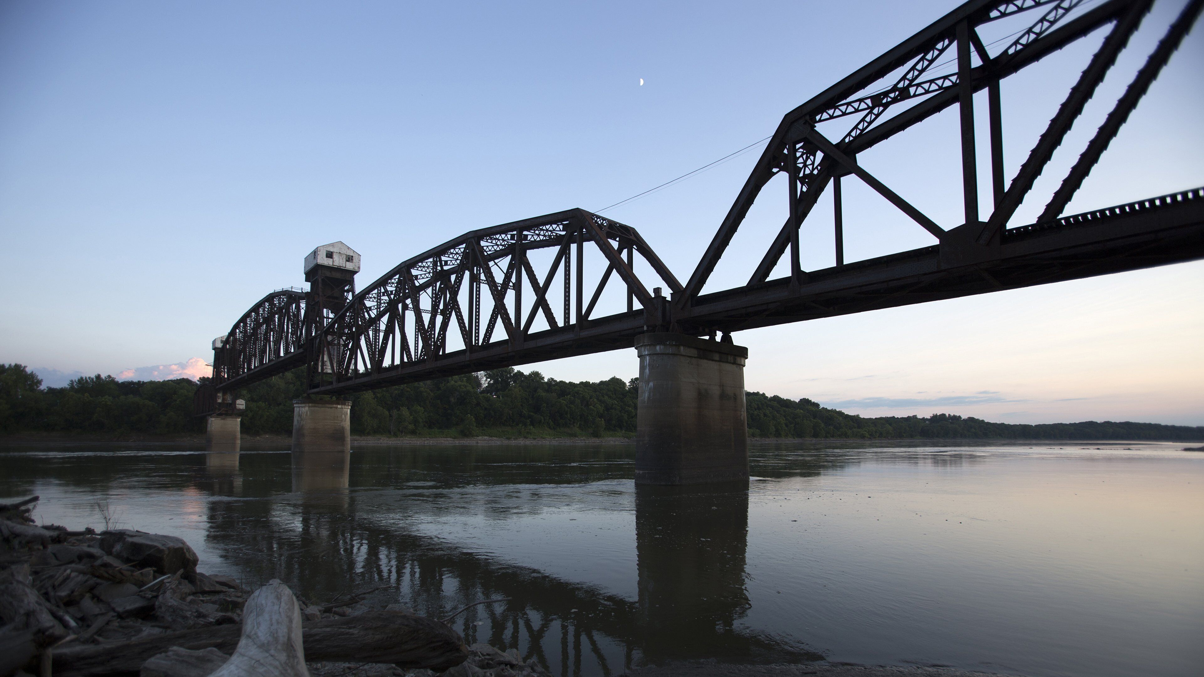 A steel bridge with a tower and a calm river below.