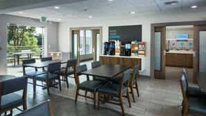 A modern cafe with tables and chairs, a coffee station, and a view of the outdoors. - Holiday Inn Express Corvallis-On the River by IHG (Corvallis)