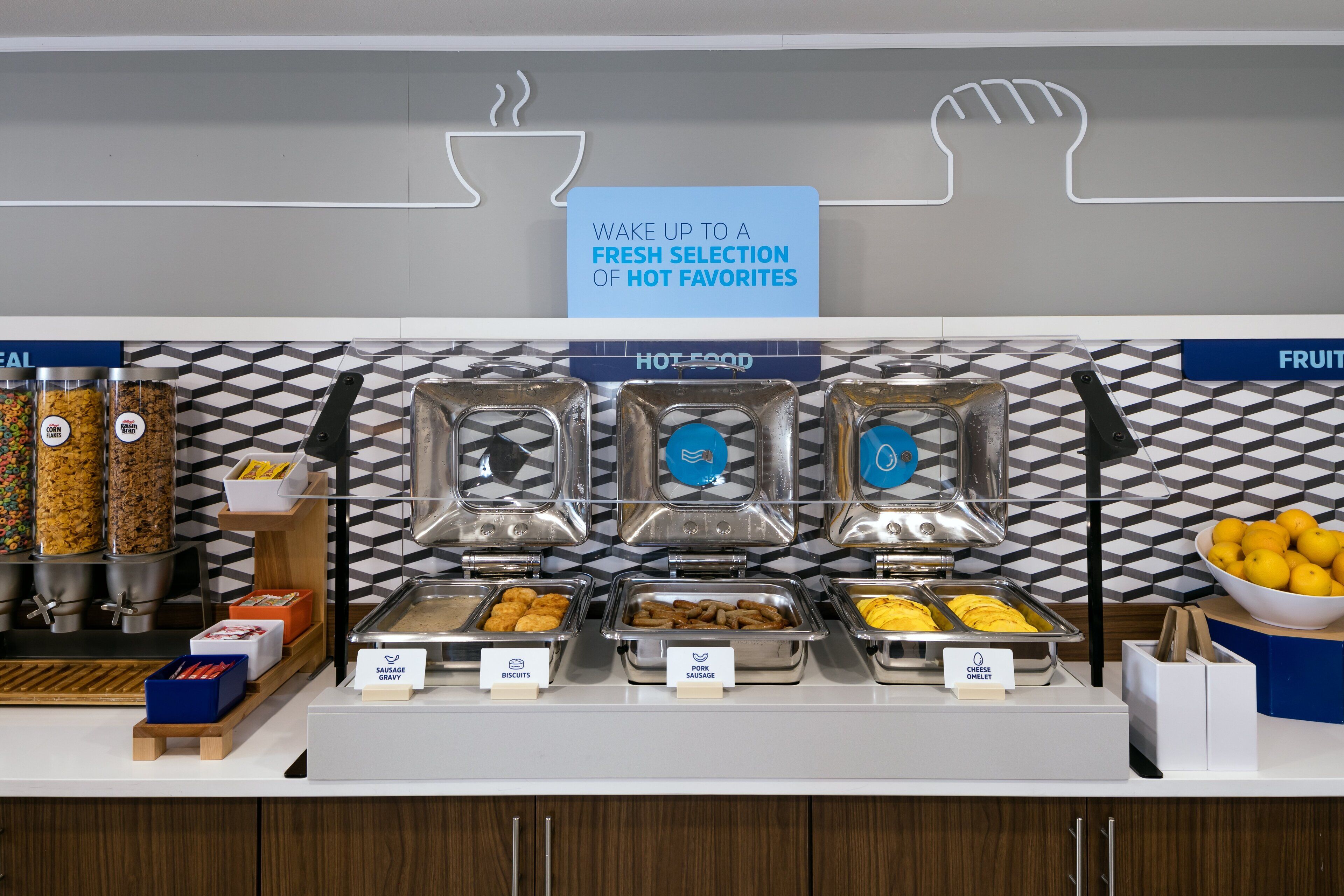 A buffet with labeled food sections including sausage, biscuits, and cheese.