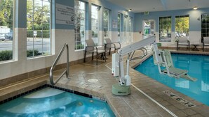 Una piscina con tablero de salto, sillas y un cartel de salvavidas.