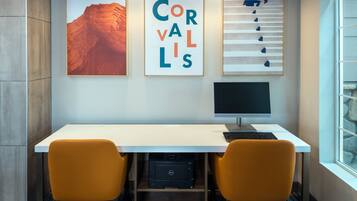 A modern office space with a white desk, two orange chairs, a Dell printer, and framed artwork on the wall.