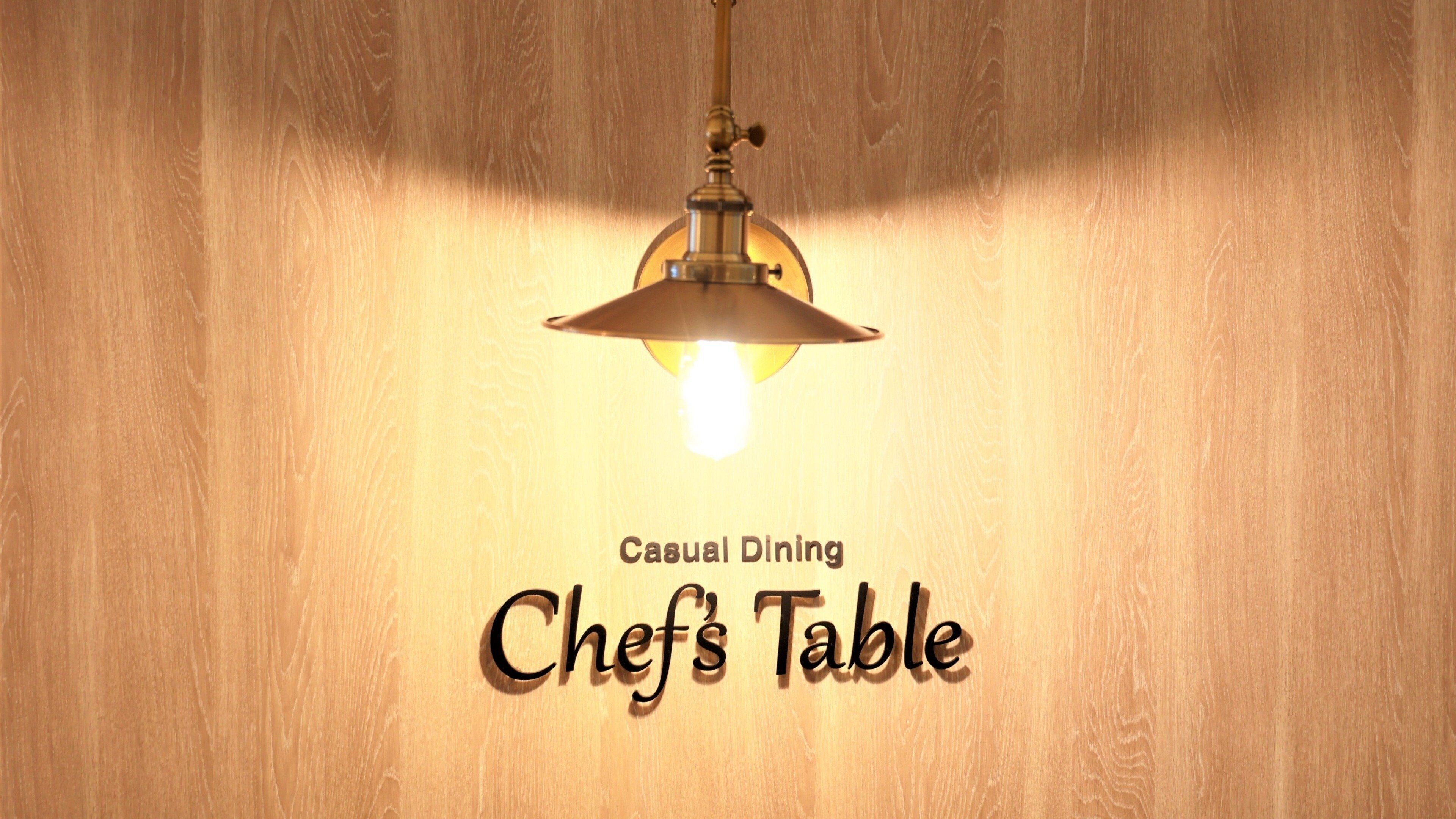 A sign with the text "Casual Dining Chef's Table" against a wooden background.