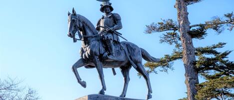 Una estatua de una figura a caballo sobre un pedestal, rodeada de árboles.