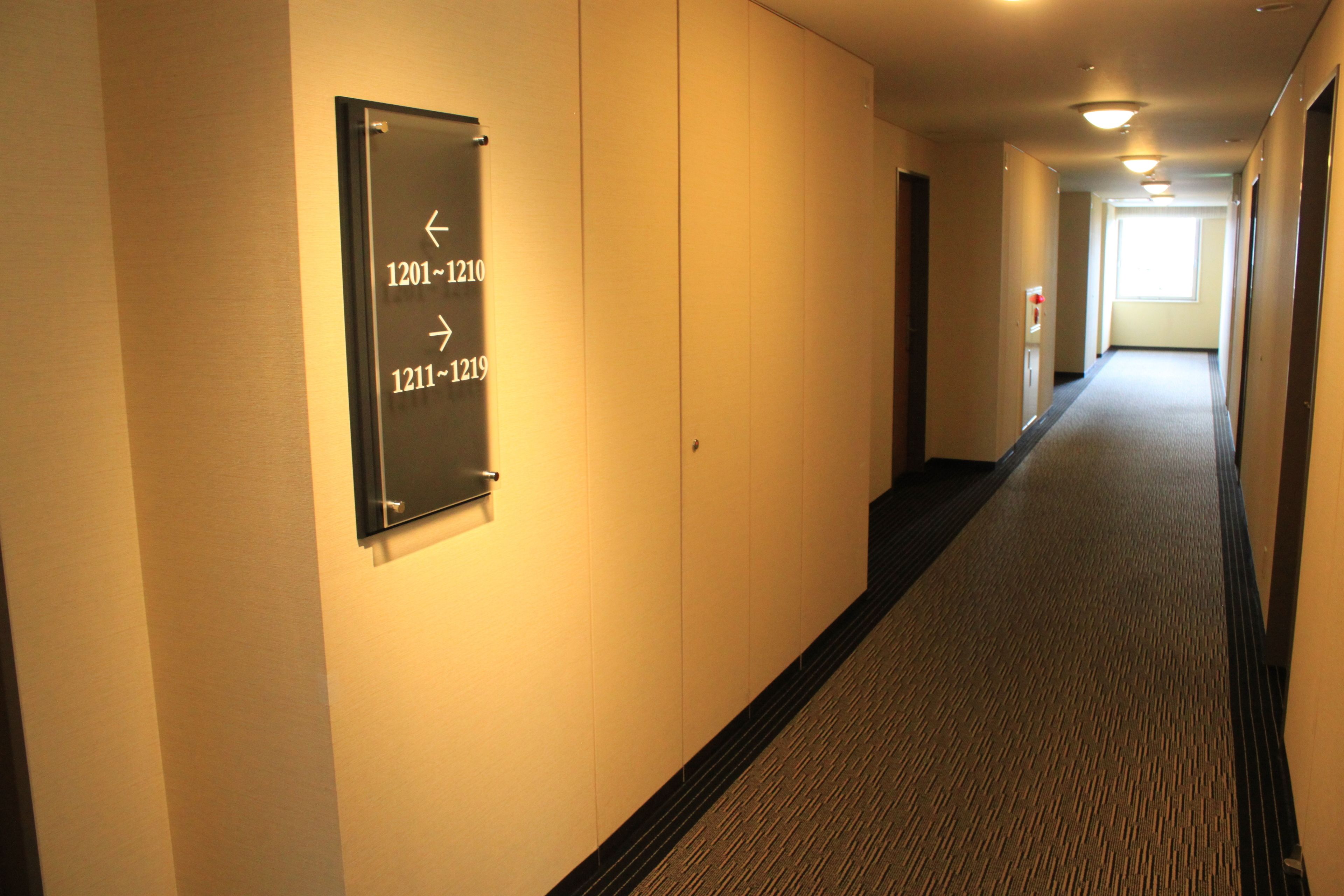 Een hotelhal met richtingwijzers die kamer nummers 1201-1210 en 1211-1219 aangeven.