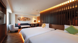 Habitación de hotel con una cama grande, un escritorio, un sofá y una lámpara de pared.