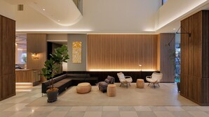 Um lobby moderno com balcão de recepção, área de estar e uma grande planta.