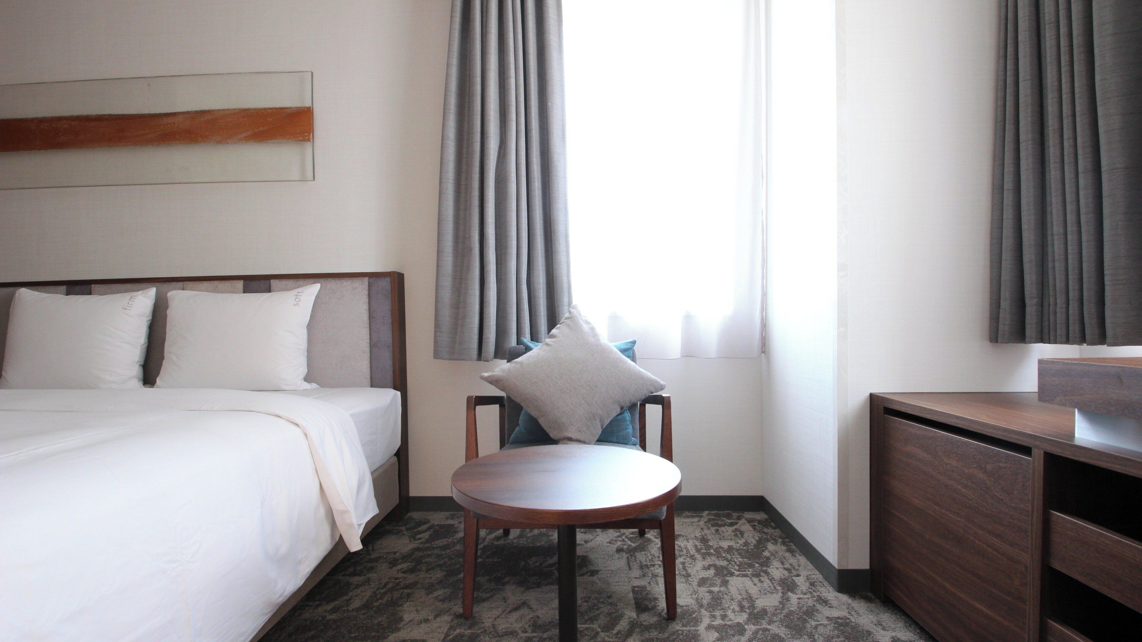 Una habitación de hotel con cama, escritorio y silla.