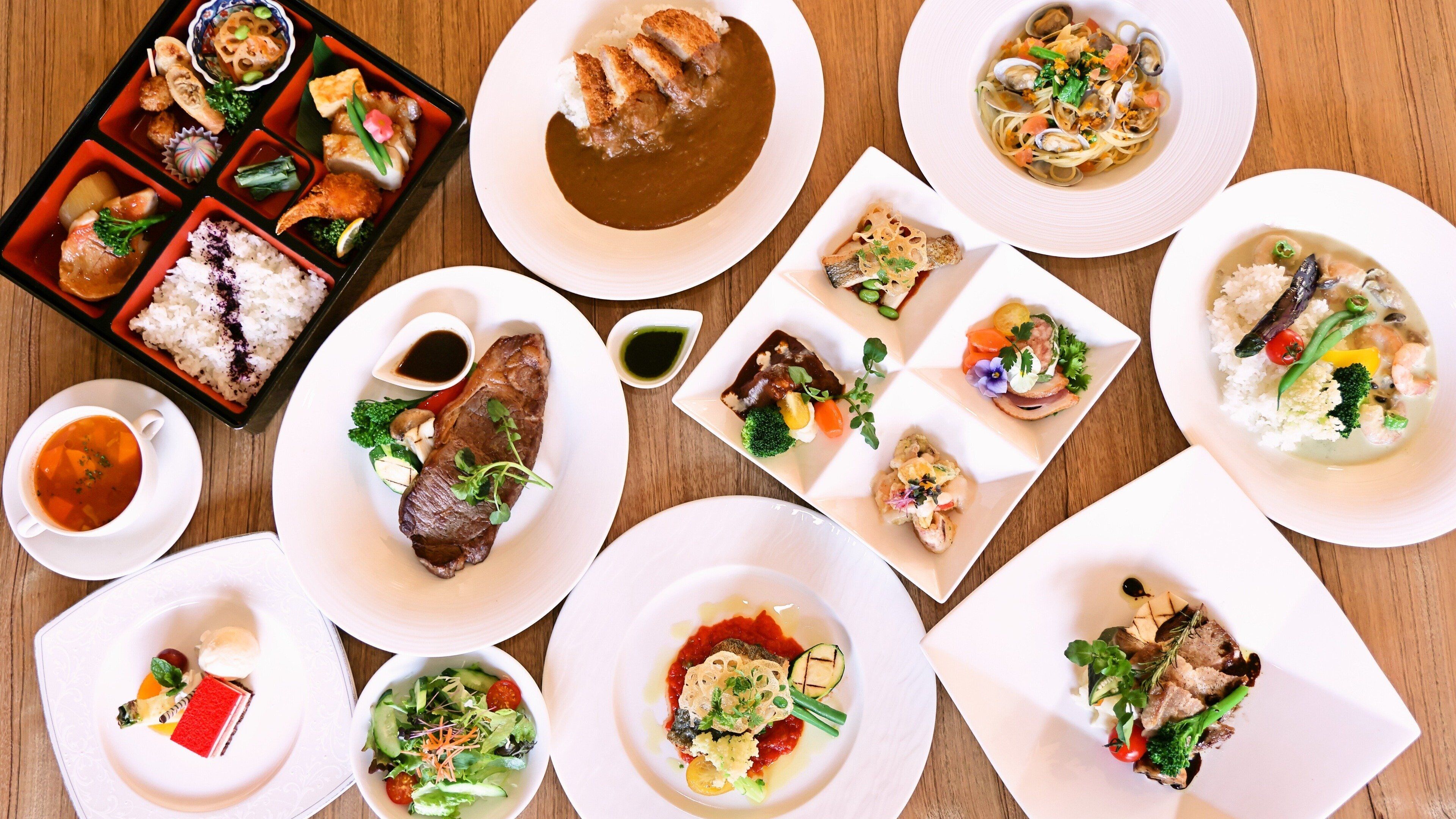A variety of dishes including sushi, sashimi, and a bowl of soup, arranged on a wooden table.