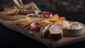 Una tabla de madera con diversos tipos de carne, quesos y verduras.