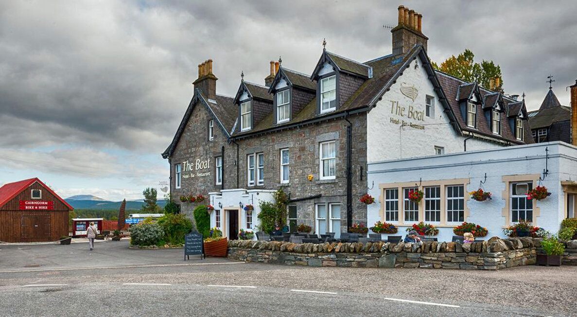 A traditional stone building with a sign reading "The Boat" and a red-roofed structure labeled "Cairngorm Bike & Hike".