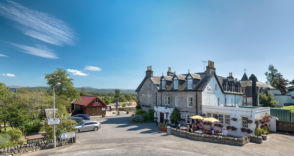 A traditional building with a sign 'The Boat' and a pub area with outdoor seating. - The Boat Hotel (Boat of Garten)