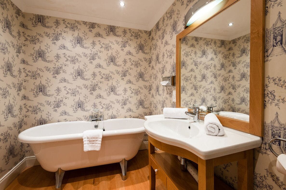 A bathroom with a freestanding bathtub, a sink, and a mirror.