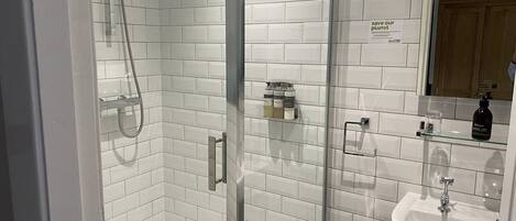 A modern bathroom with white subway tiles, a glass shower enclosure, a sink, and a mirror.