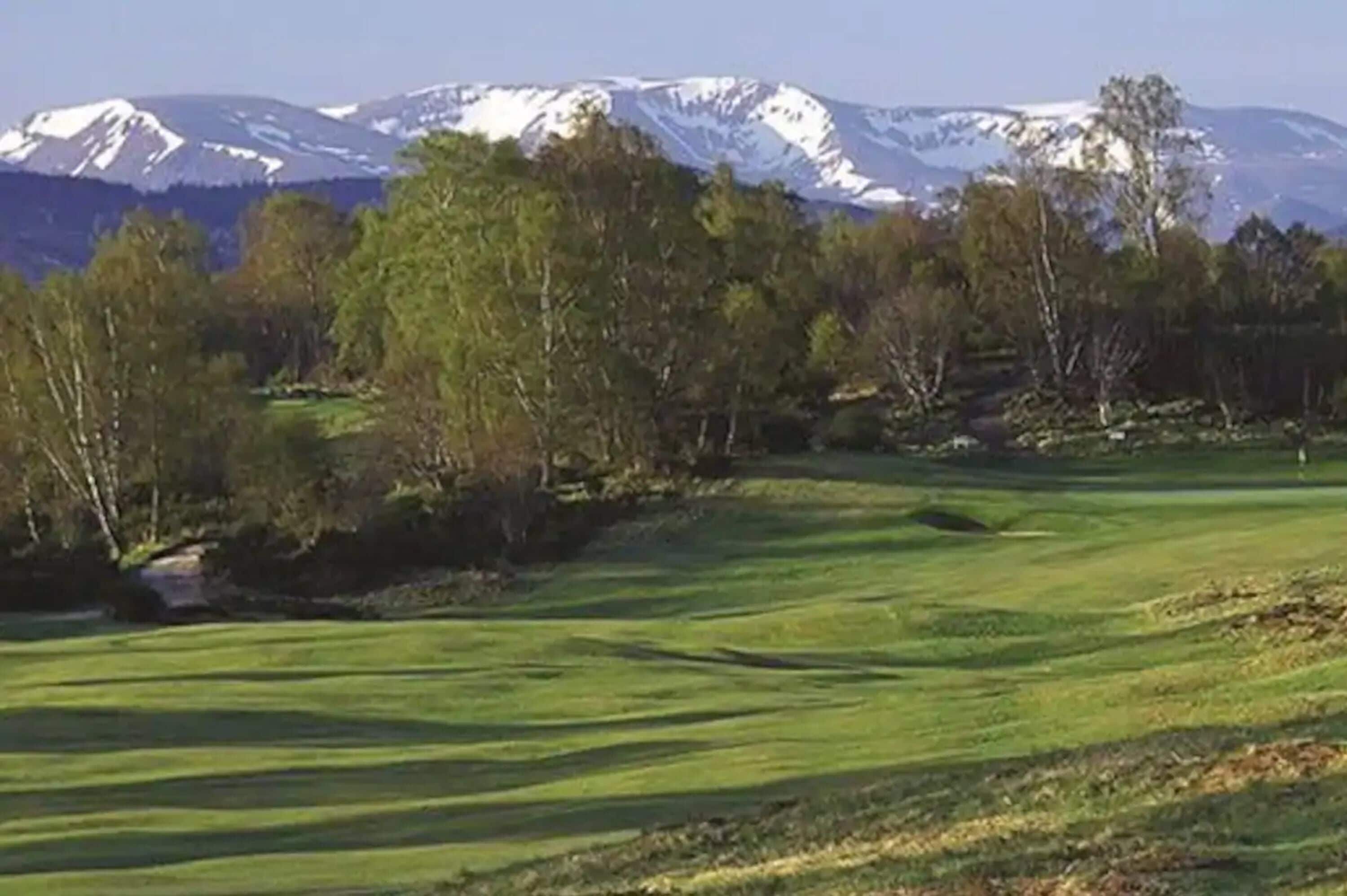 Un campo de golf con montañas al fondo.