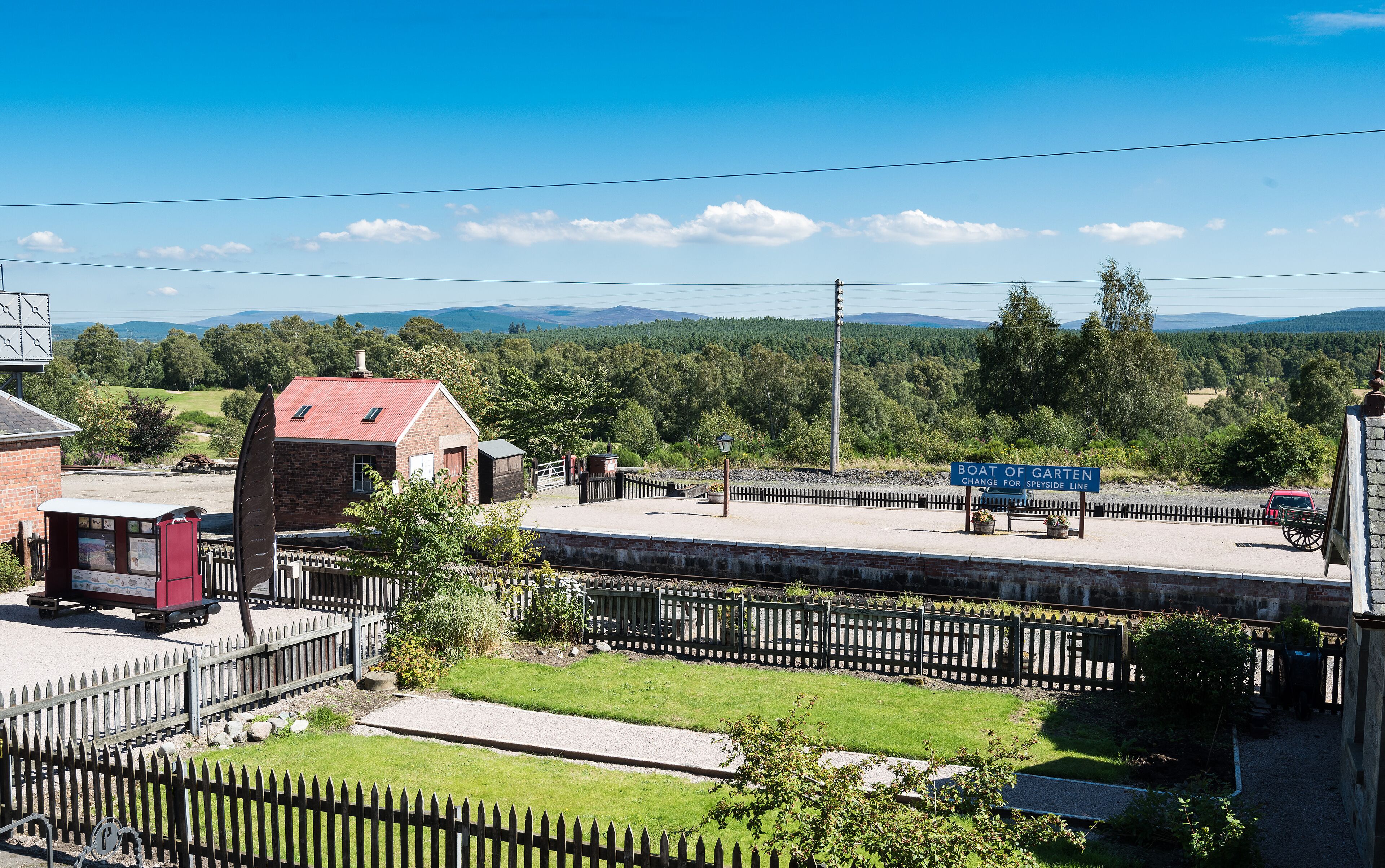 En järnvägsstation med en skylt som visar ”Boat of Garten” och där man kan byta till tåget som går längs Speyside-linjen.