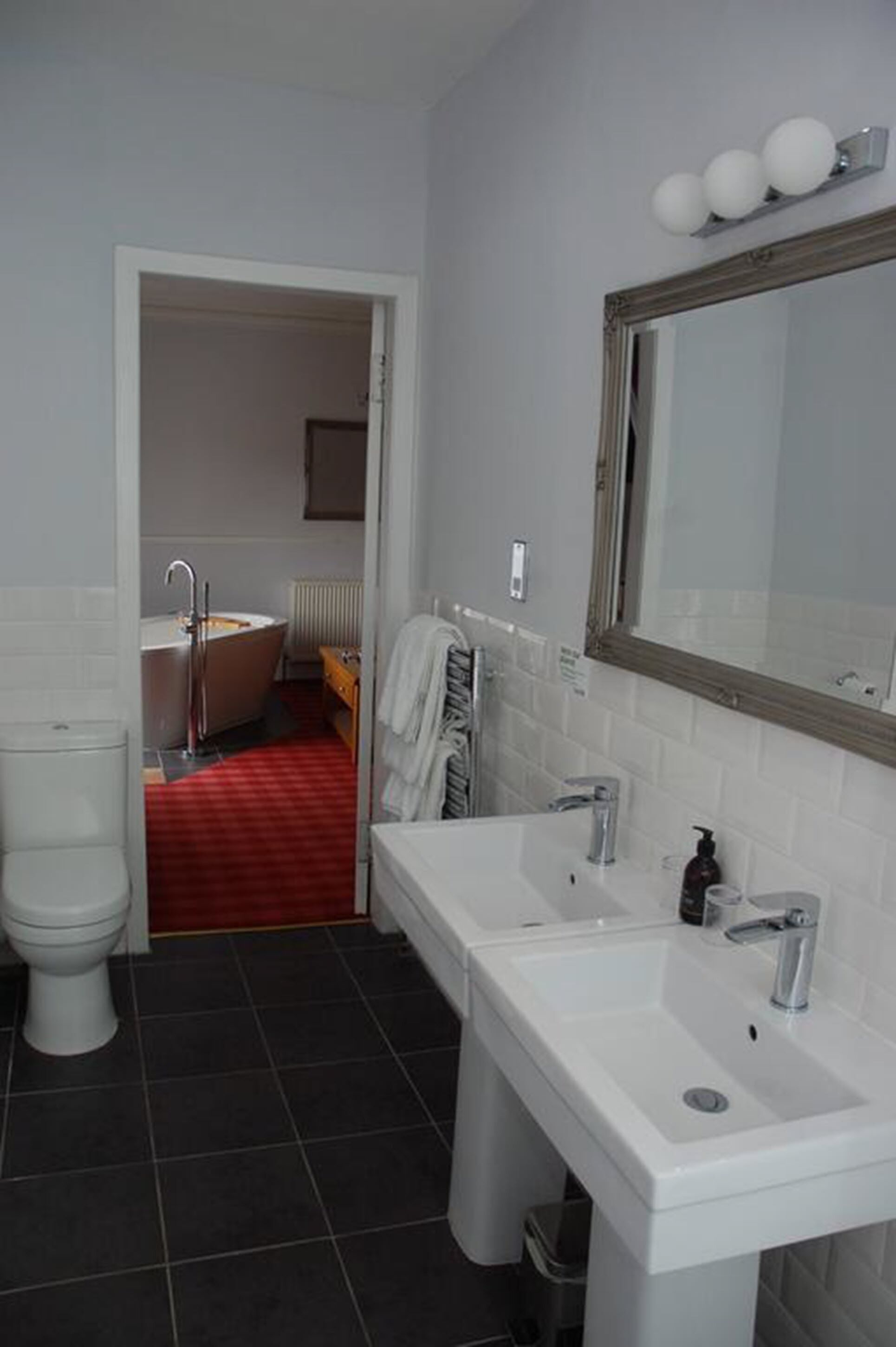 A bathroom with a white toilet, a sink with a mirror, and a bathtub.