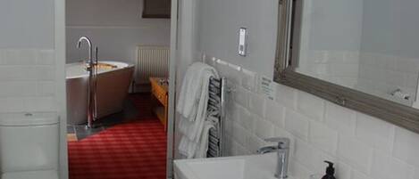 A bathroom with a white toilet, a sink with a mirror, and a bathtub.