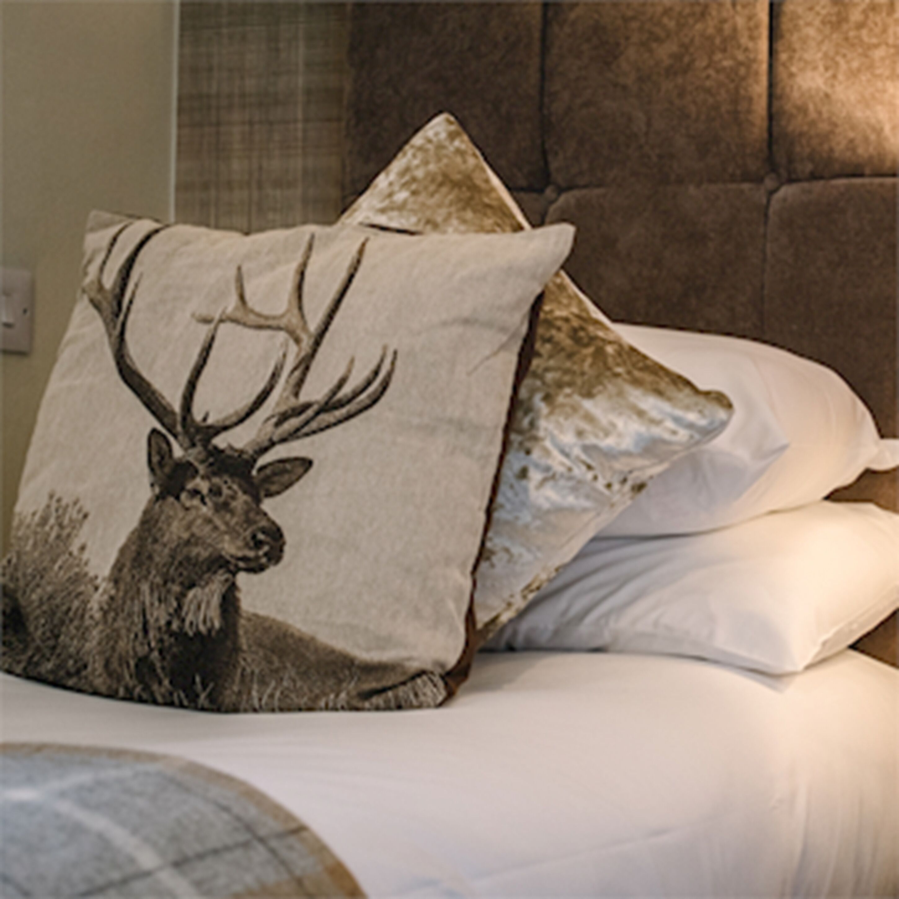 A bed with a pillow featuring a deer illustration.