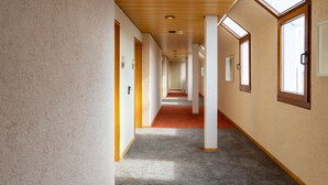 A long, narrow hallway with wooden ceiling panels and large windows on one side. - Filderhotel (Ostfildern)
