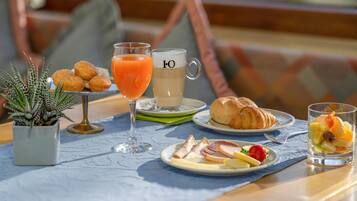 Una mesa con croissants, fruta y jugo para el desayuno.