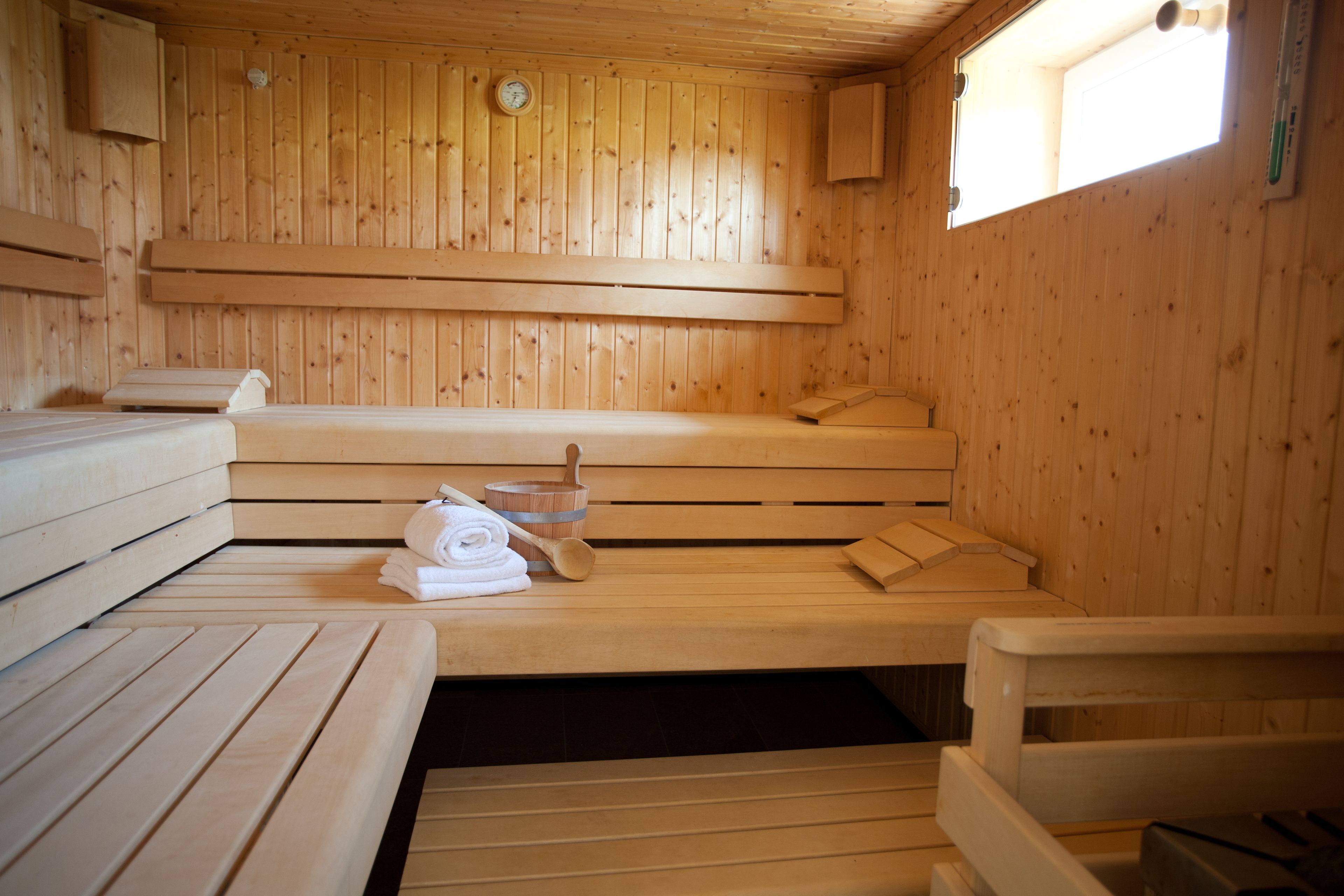 A wooden sauna with benches, a wooden bench, and a towel on the bench.