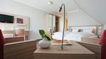 A modern hotel room with a bed, bedside table, and a TV mounted on the wall.