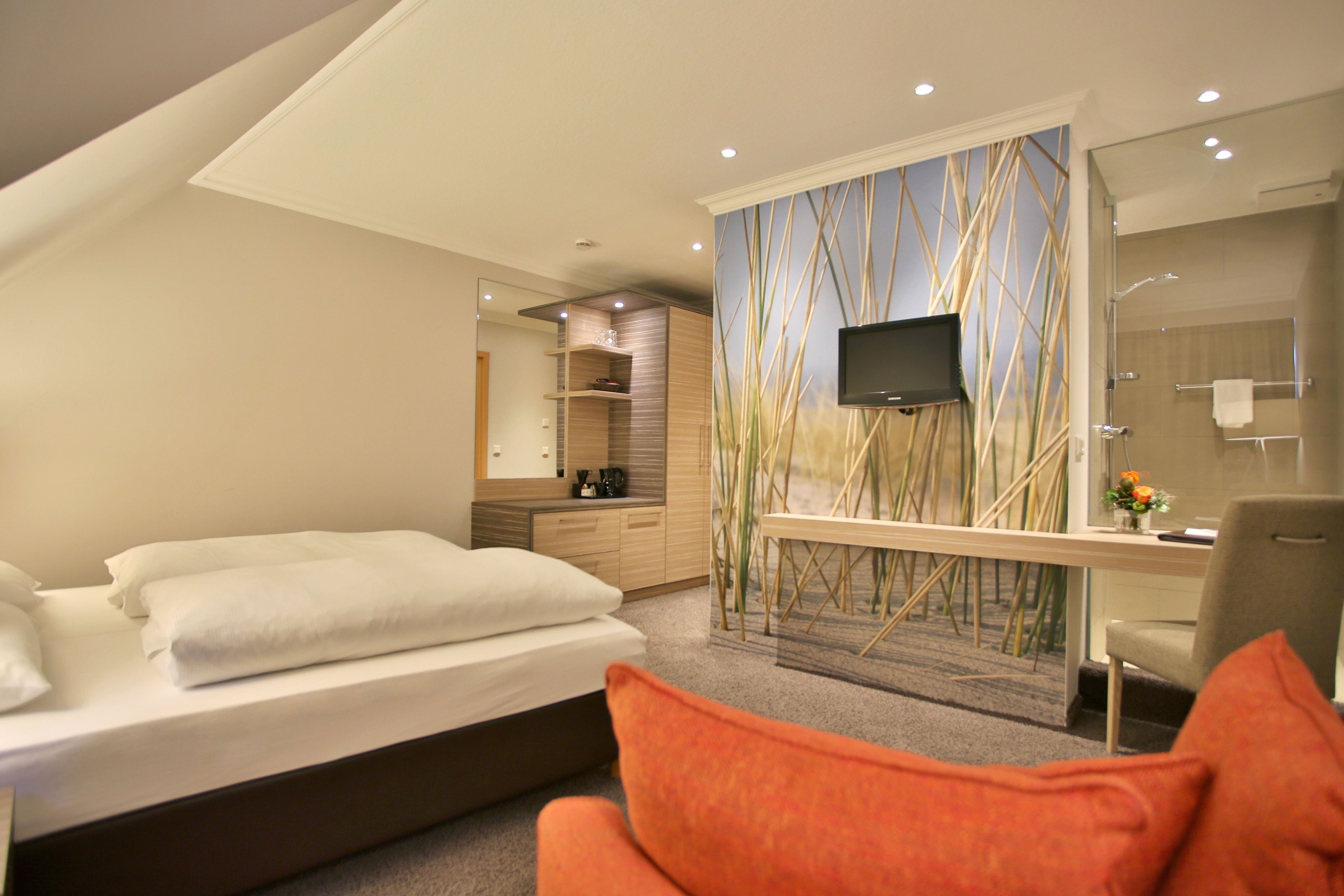 Une chambre d’hôtel moderne équipée d’un lit, d’un bureau, d’une chaise, d’une télévision et d’une salle de bain.