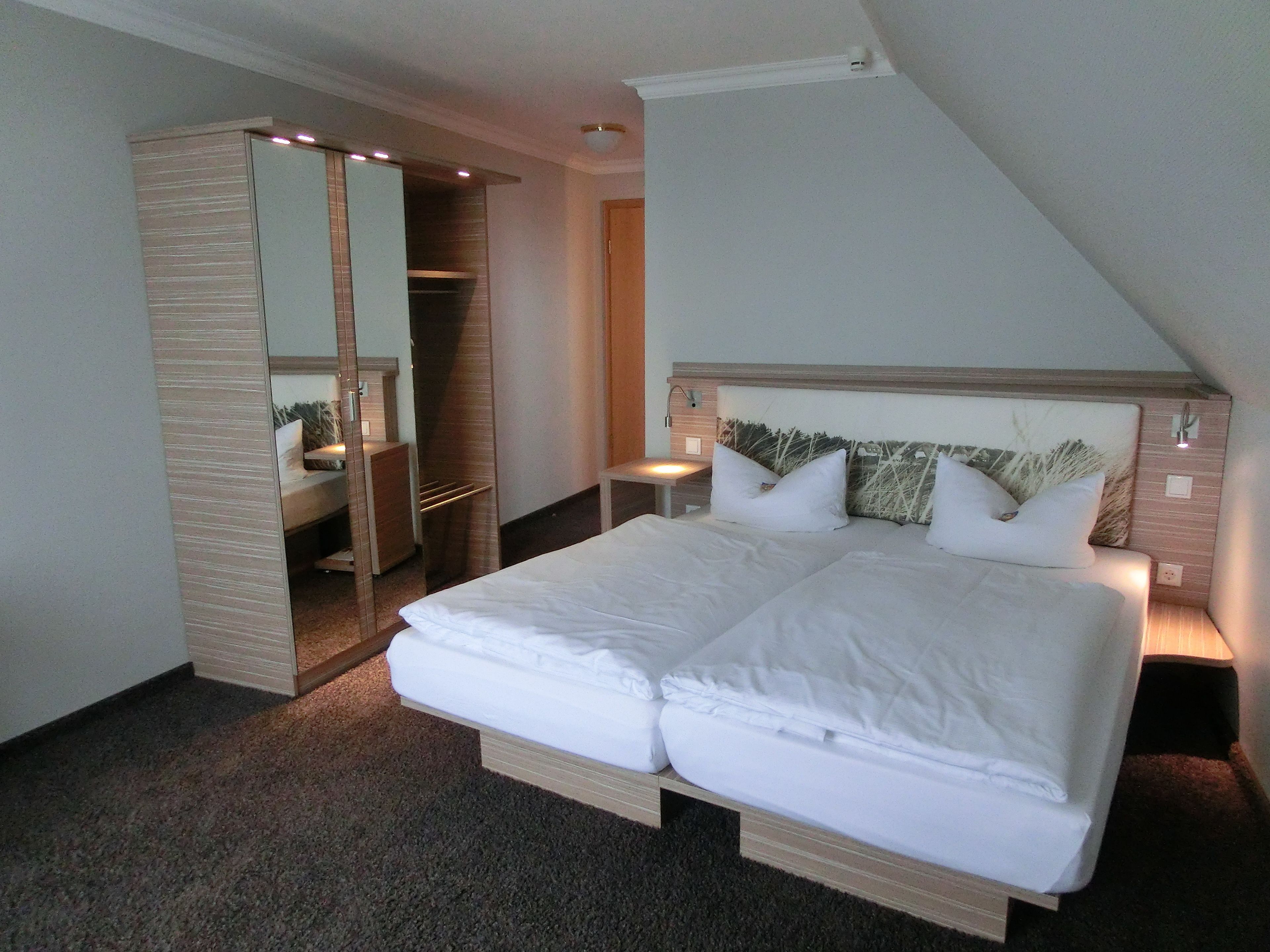Ein Schlafzimmer mit einem großen Bett, einem Nachttisch, einem Spiegel und einem begehbaren Kleiderschrank.