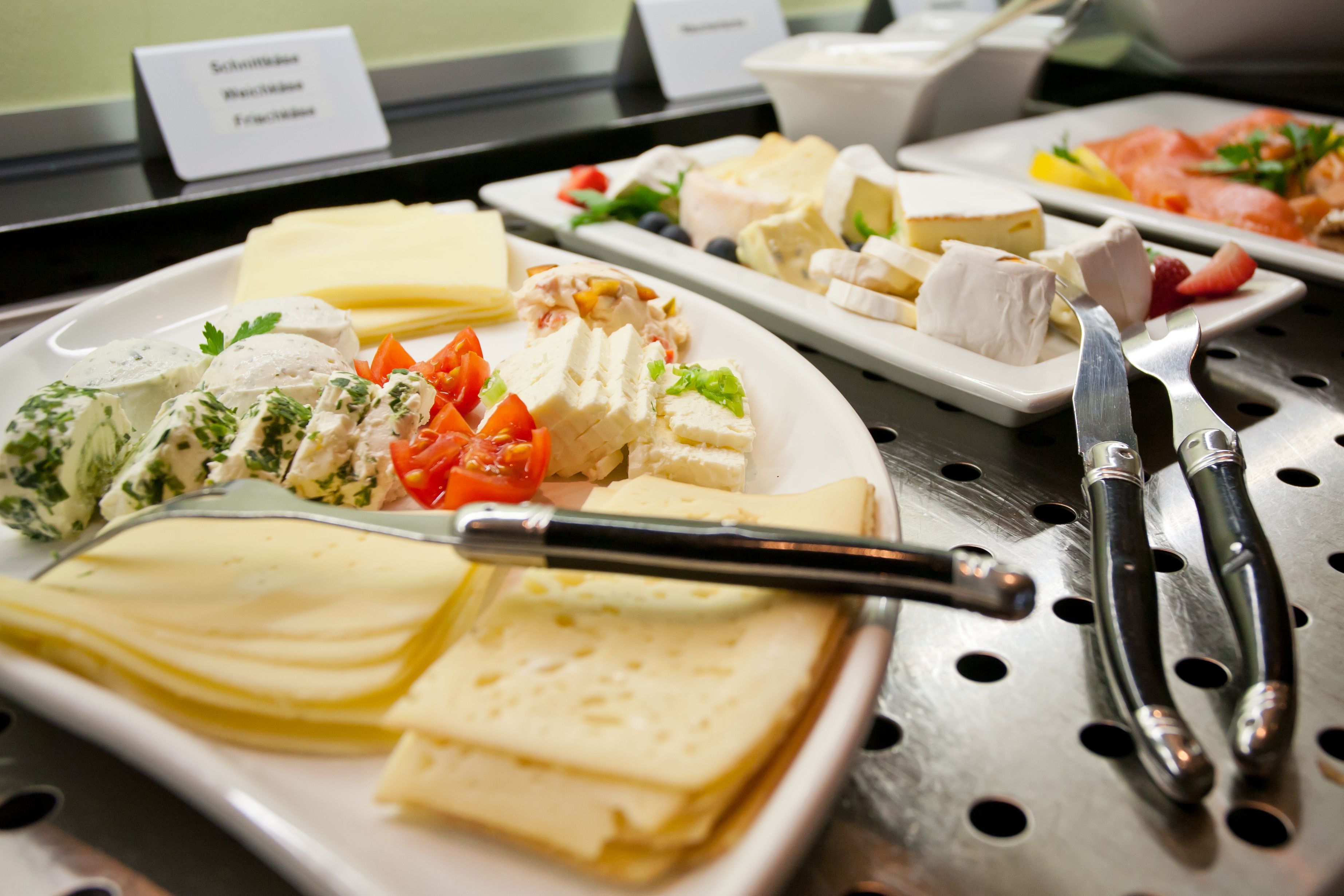 Um buffet com diversos queijos, frutas e legumes.