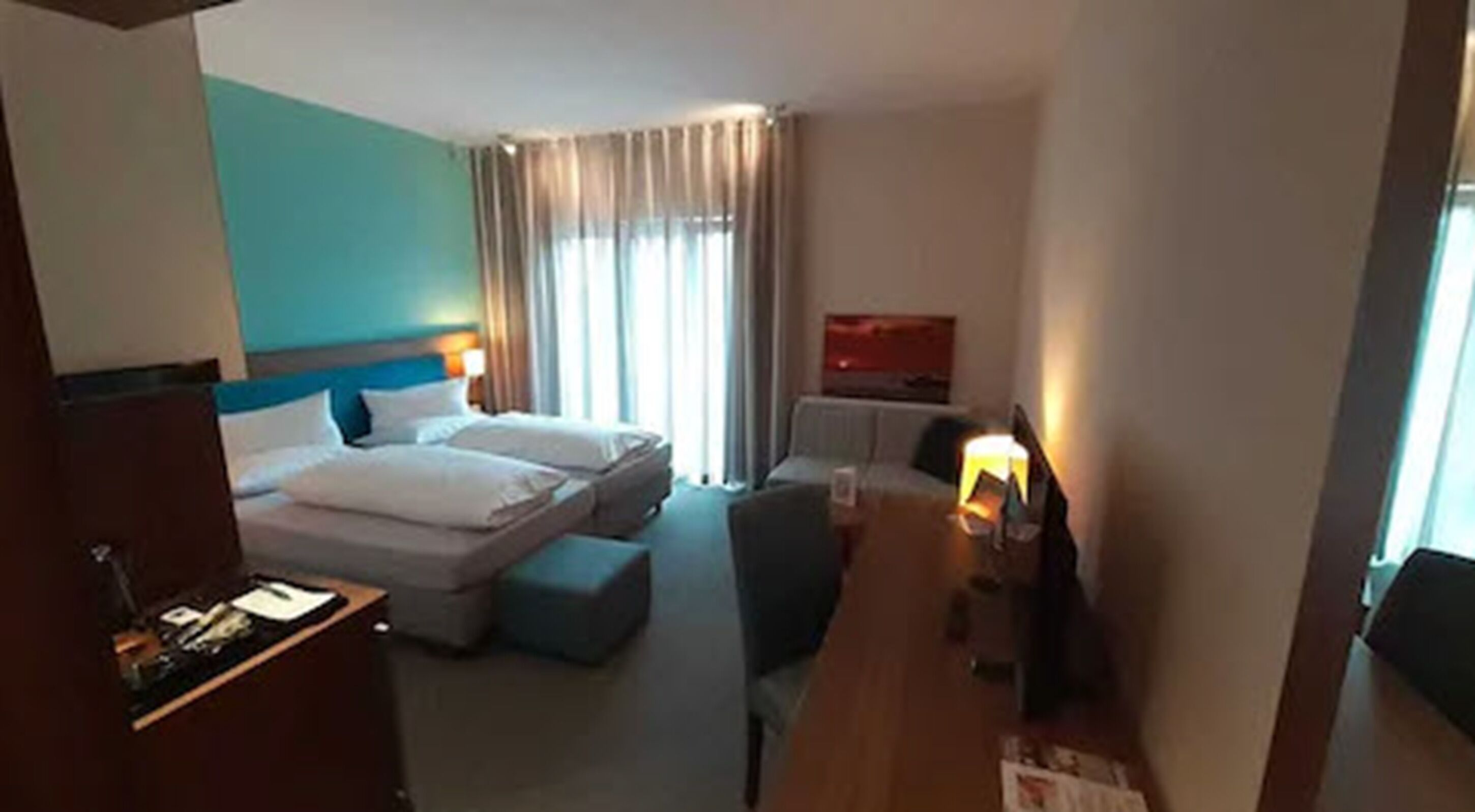 A hotel room with two beds, a desk, and a TV.