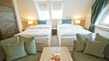 A hotel room with two beds, a small table, and a view of the city through skylights.