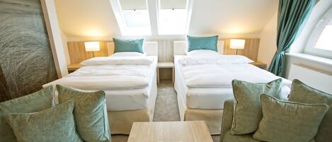 Habitación de hotel con dos camas, una mesita y vistas a la ciudad a través de tragaluces.