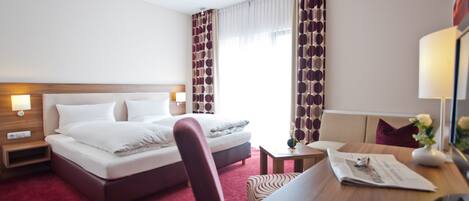 Una habitación de hotel con cama, mesitas de noche, escritorio y una silla.