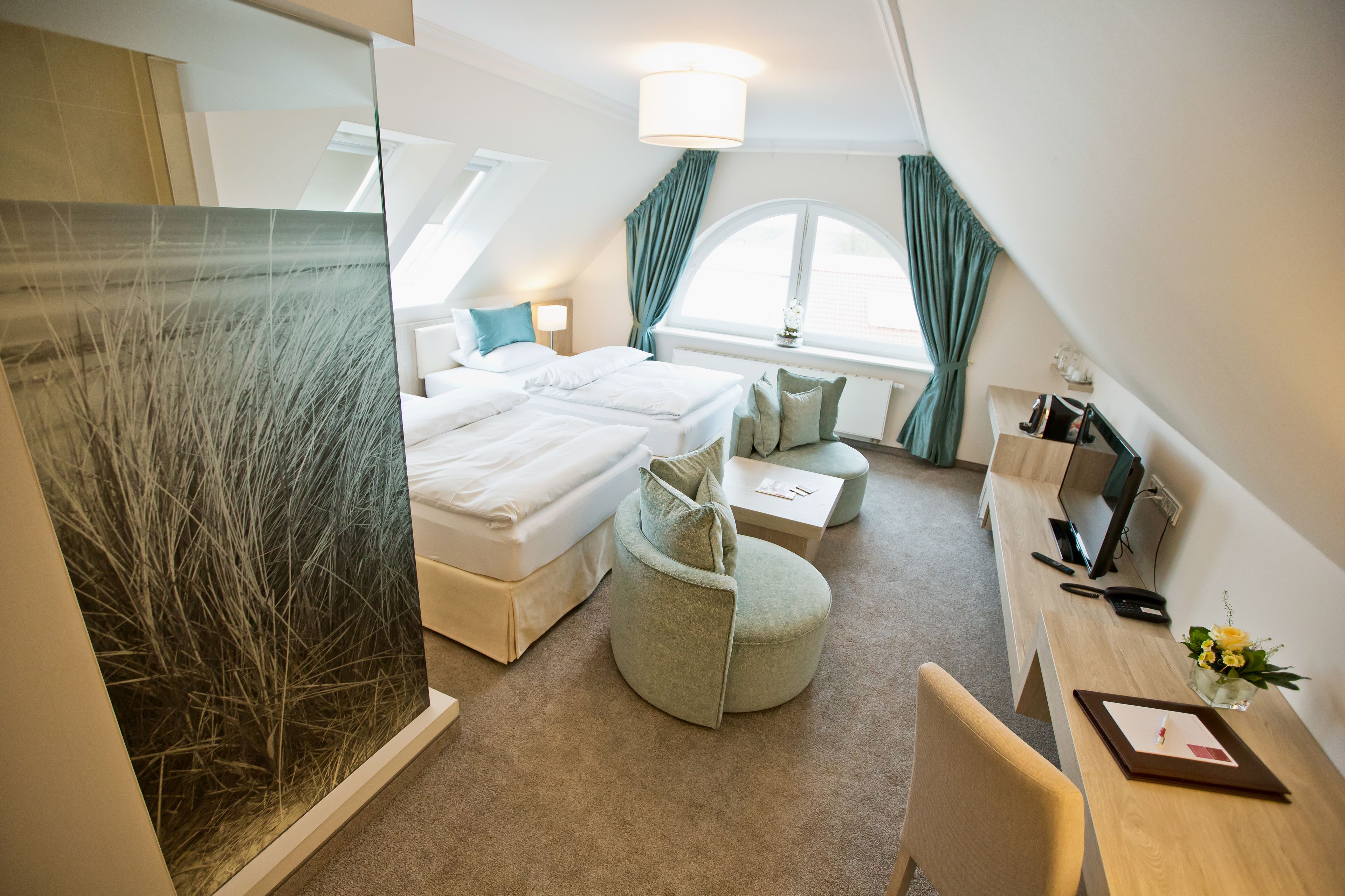 A modern hotel room with two beds, a desk, a chair, and a large window with curtains.