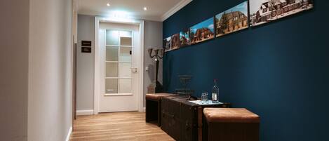 A hallway with wooden flooring, a bench, a cabinet, and a wall with framed pictures.