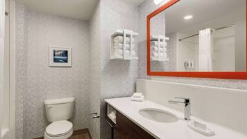 Un baño moderno con inodoro, lavamanos con espejo y barras para toallas.