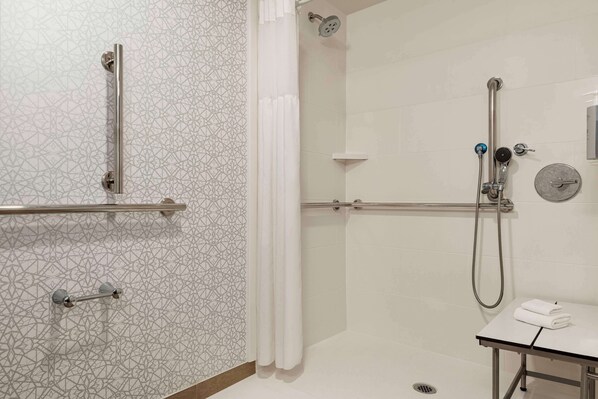 A modern bathroom with a shower, grab bars, a towel rack, and a sink. - Hampton Inn Waynesboro/Stuarts Draft (Fishersville)