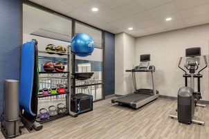 Academia com esteira, elíptica, pesos e bolas de exercício.
