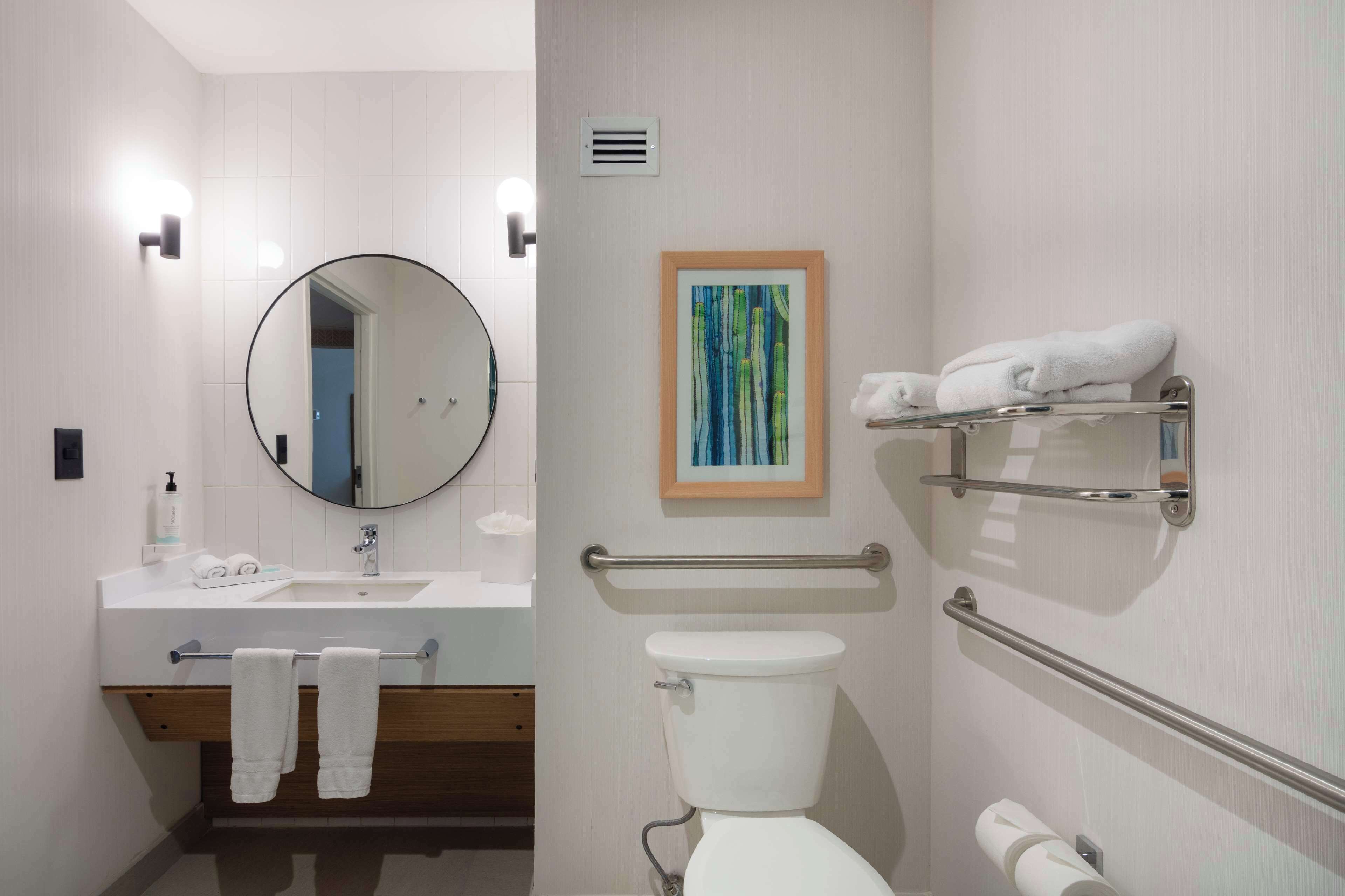 A modern bathroom with a sink, mirror, toilet, and towel racks.