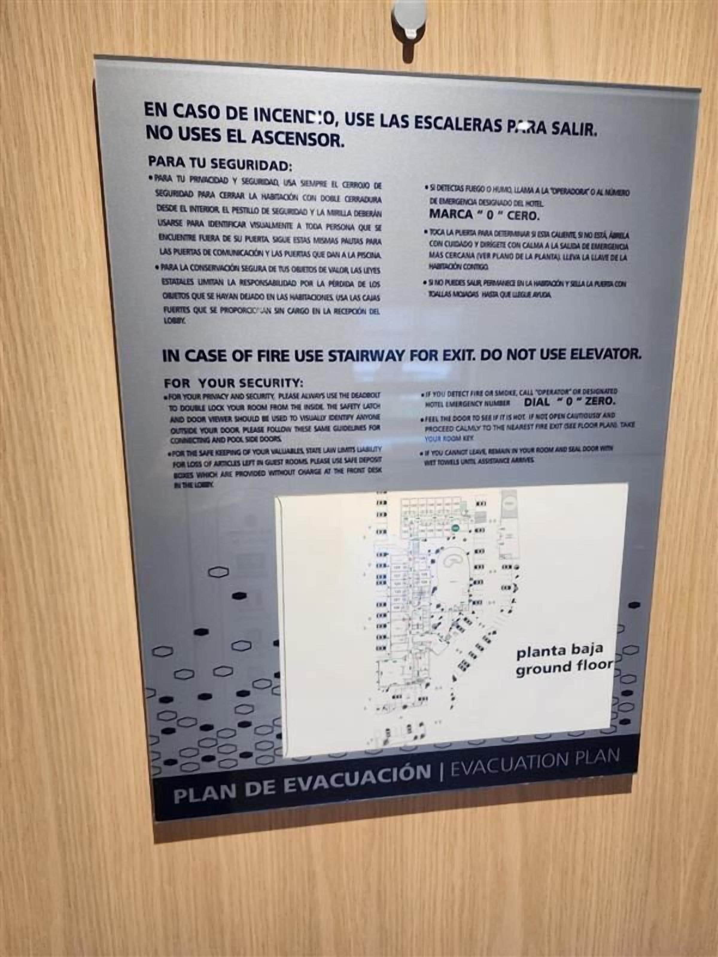 Een poster met een noodplan en instructies voor het gebruik van trappen bij brand, inclusief een plattegrond van de begane grond.