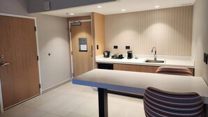 A compact kitchen with a white countertop, a built-in sink, and a striped chair. - Hampton by Hilton Saltillo (Saltillo)