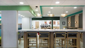 A modern kitchen with a central island, bar stools, and pendant lighting. - Hampton by Hilton Saltillo (Saltillo)