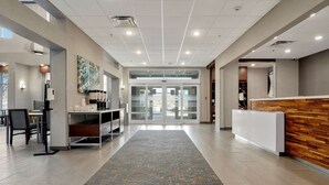 En moderne hotellobby med reception, siddeområde og et mønstret tæppe.