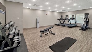 Et fitnesscenter med løbebånd, crosstrainere og vægtbænke.