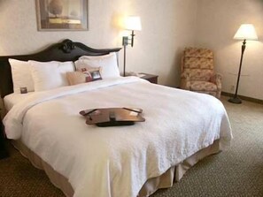 A hotel room with a large bed, two bedside lamps, a chair, and a framed picture on the wall. - Hampton Inn Dublin (Dublin)