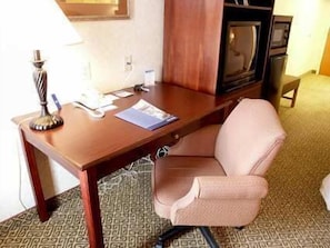 A hotel room with a wooden desk, a television, a lamp, and a patterned carpet. - Hampton Inn Dublin (Dublin)