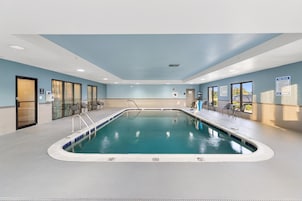 Piscina interior con agua cristalina, una silla de salvavidas y un cartel con las normas de la piscina.