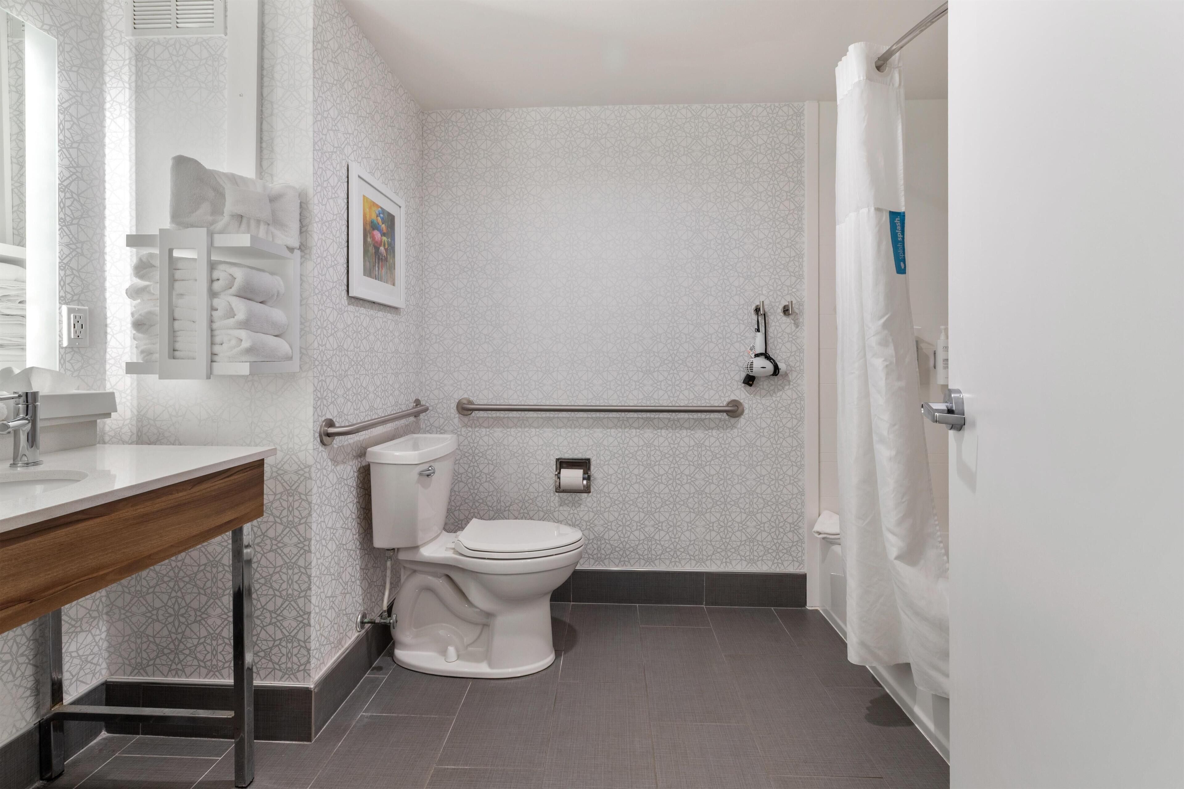 Een badkamer met toilet, wastafel, handdoekhouder en een handgreep.