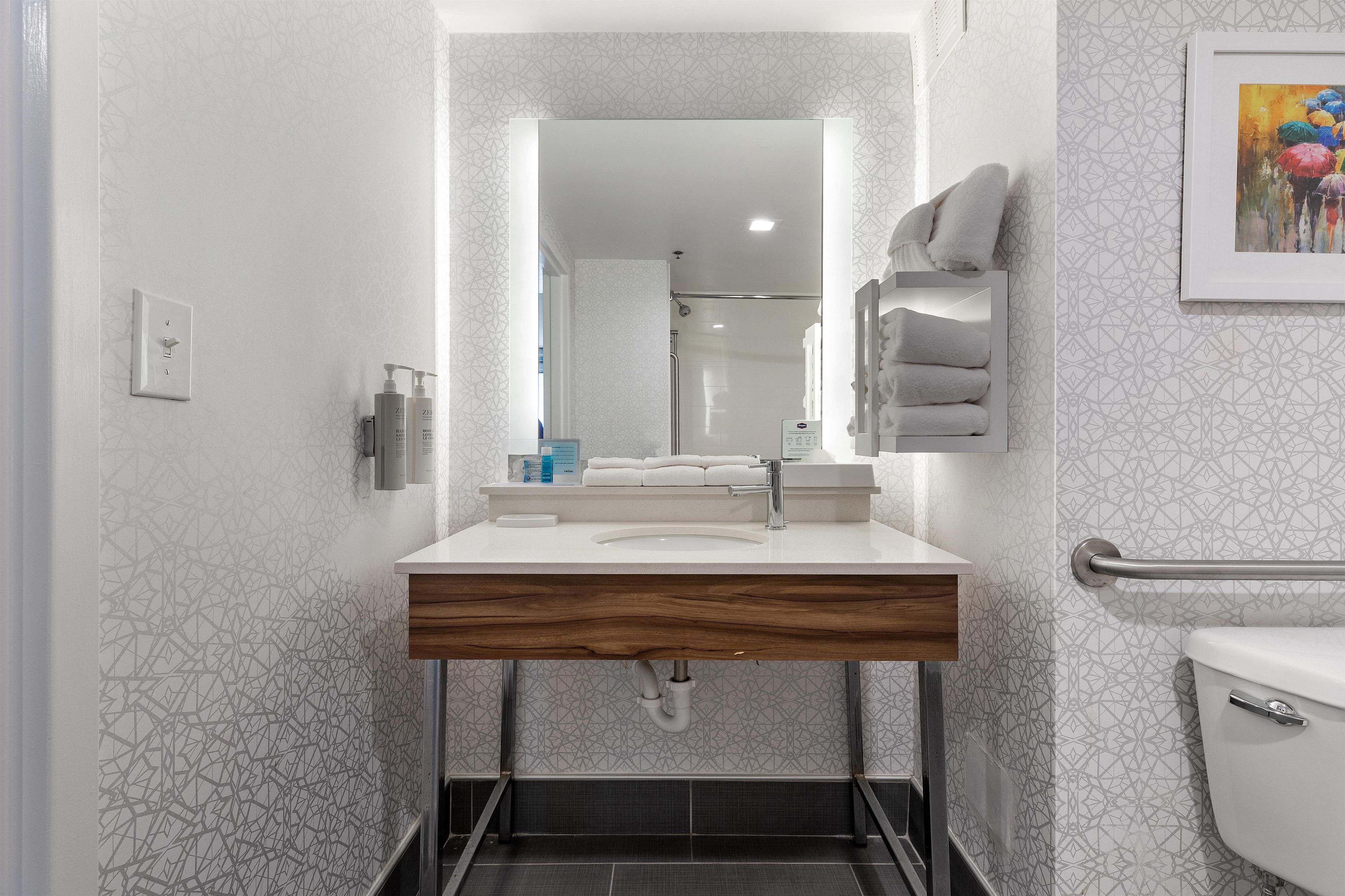 A modern bathroom with a vanity, mirror, towel rack, and a toilet.