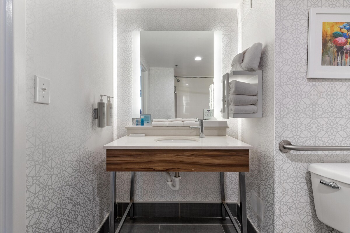 Un baño moderno con tocador, espejo, toallero y un inodoro.